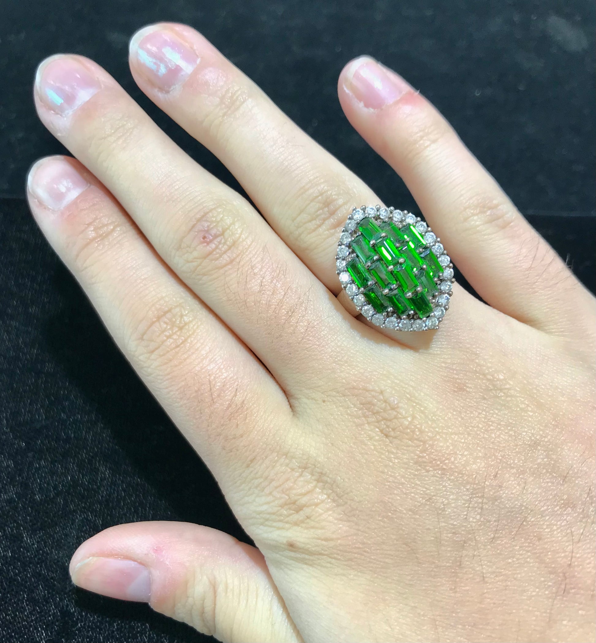 A sterling silver marquise shape ring set with green baguette cut stones.