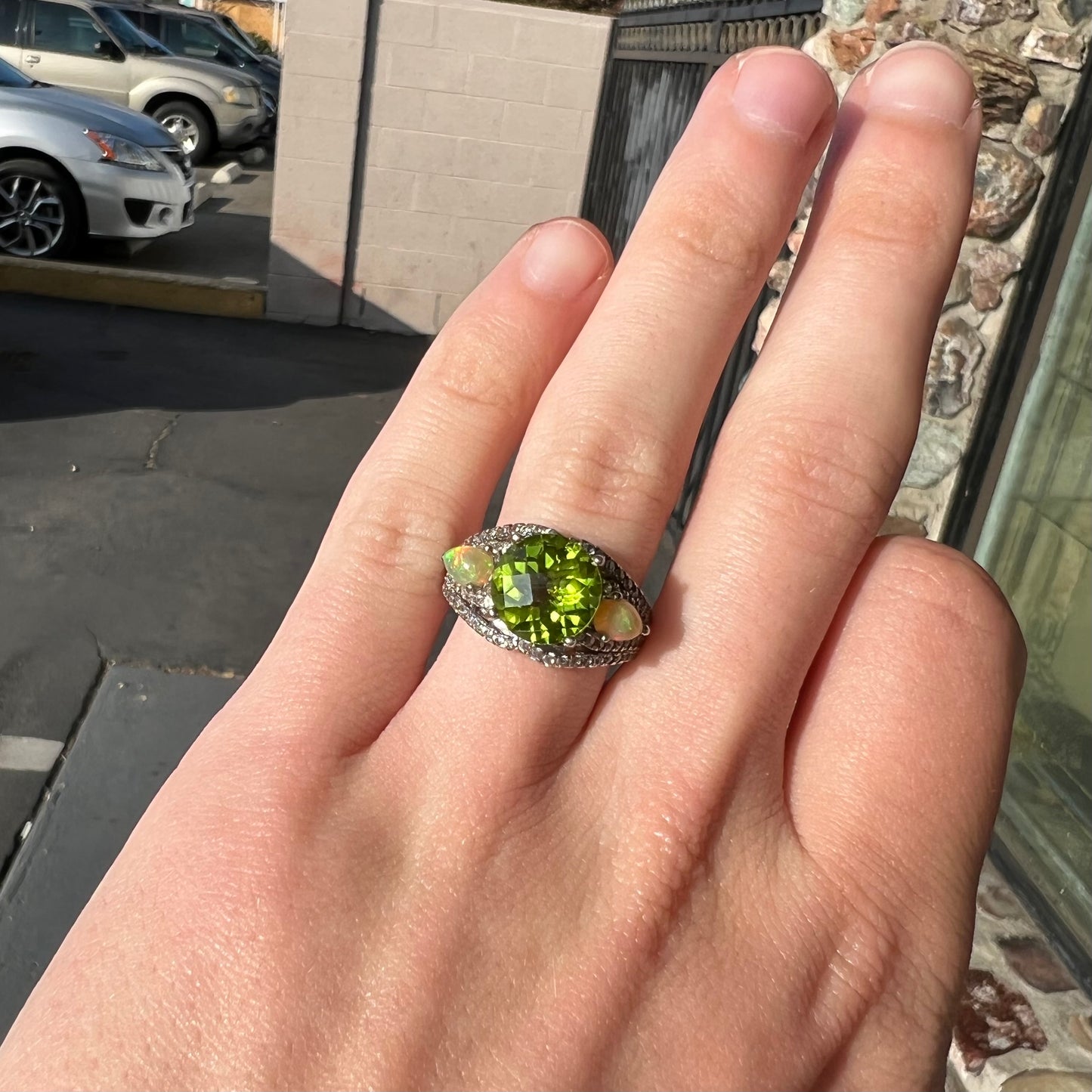 A sterling silver ring set with one large round peridot stone set between two pear shape cabochon Ethiopian opals.  Cubic zirconia stones line the ring.