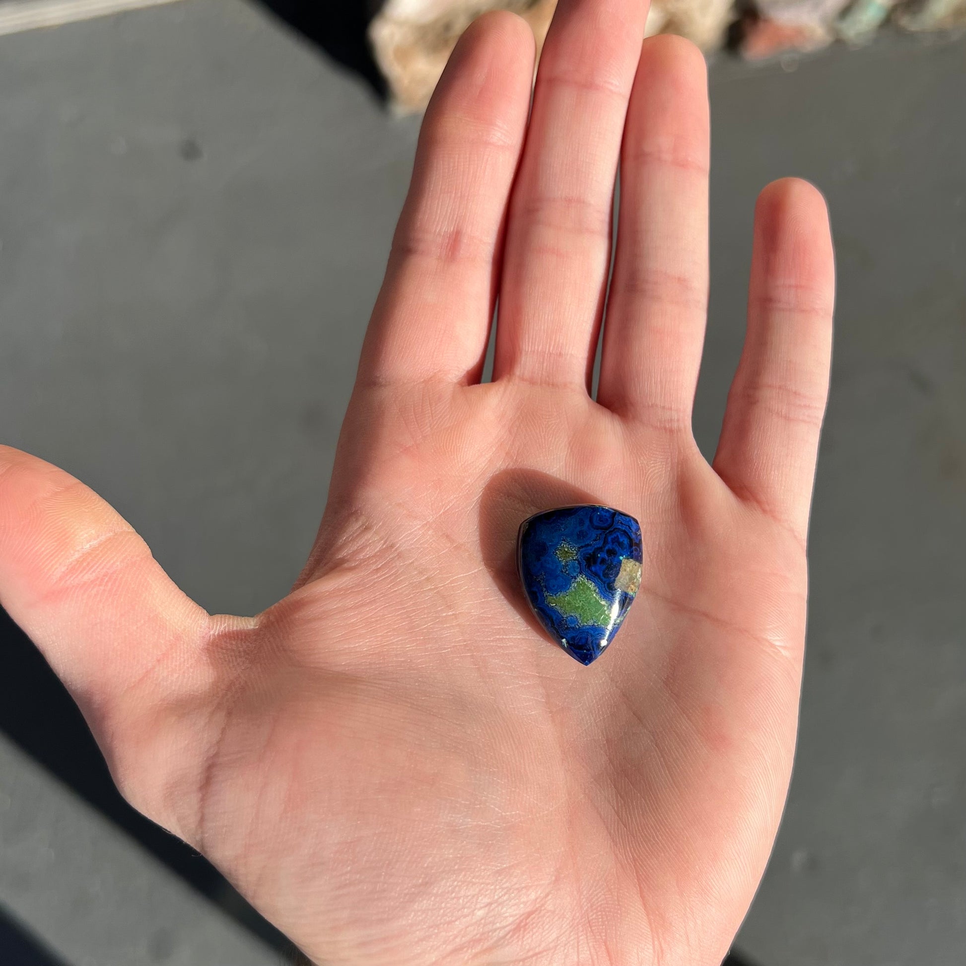A loose pear shape cabochon cut blue azurite stone with green pseudomalachite inclusions.