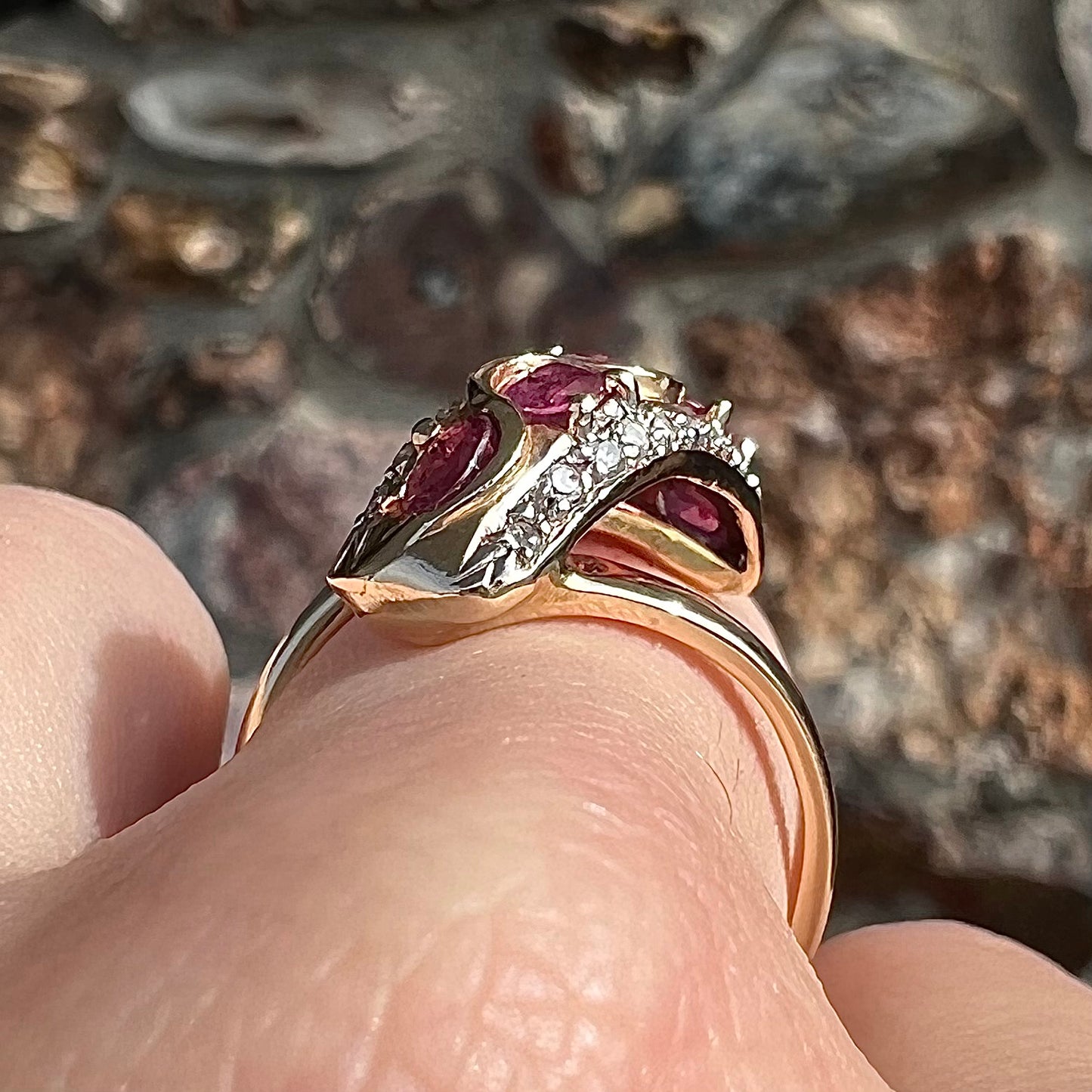A custom freeform design yellow gold twisted shank ring set with five oval cut rubies and small round diamonds.