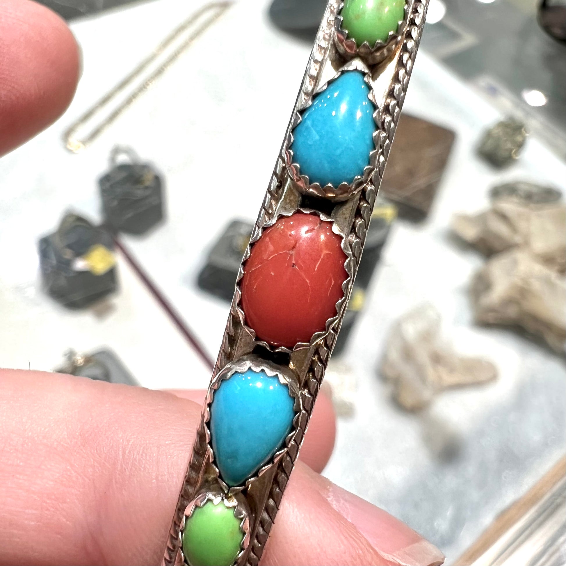 A silver rope cuff bracelet set with coral, turquoise, gaspeite, and lapis lazuli stones.  The underside is stamped "Daniel Mike".