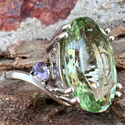 A sterling silver oval cut prasiolite ring set with two pear shaped tanzanite accent side stones.