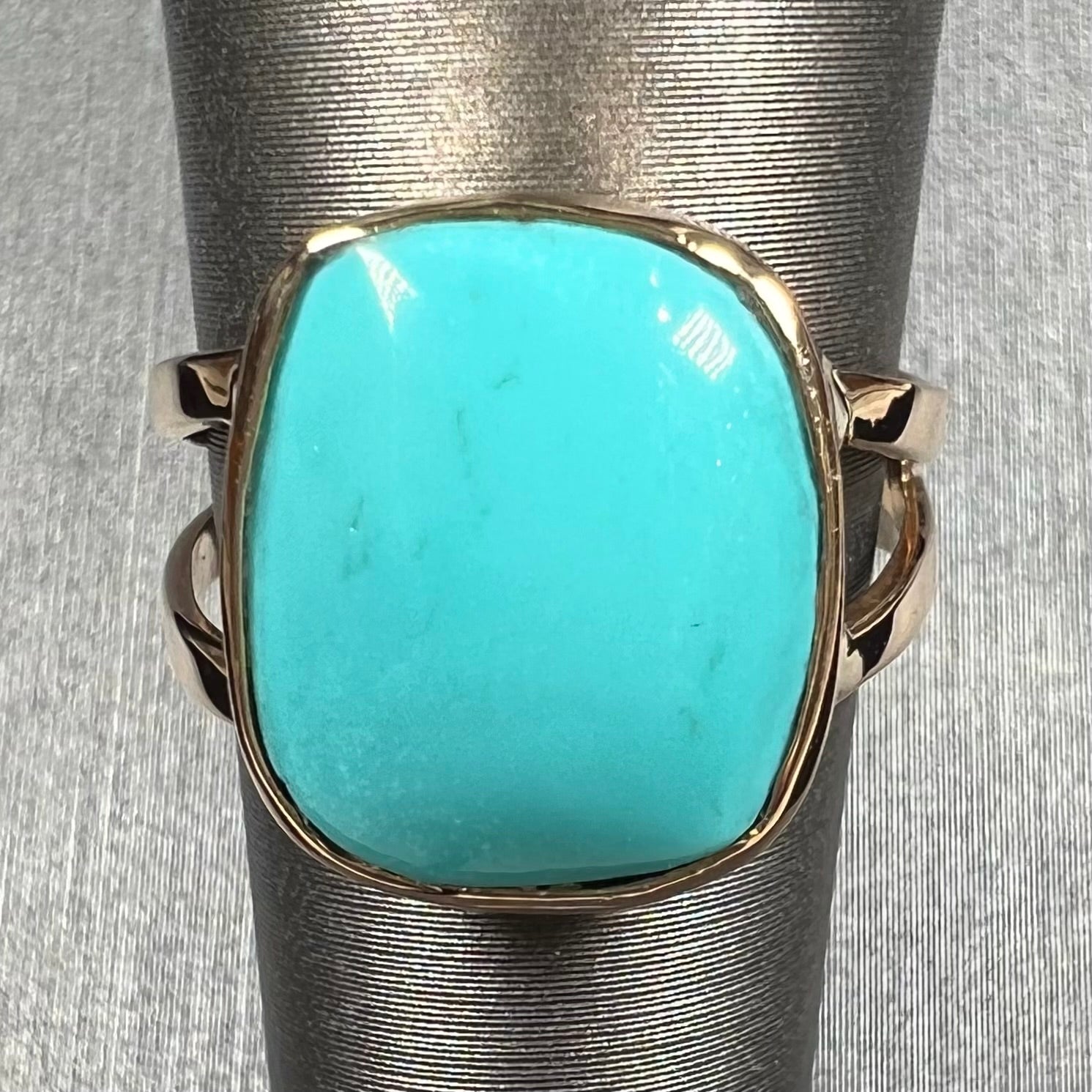 A handmade split shank ring set with Sleeping Beauty turquoise in yellow gold.