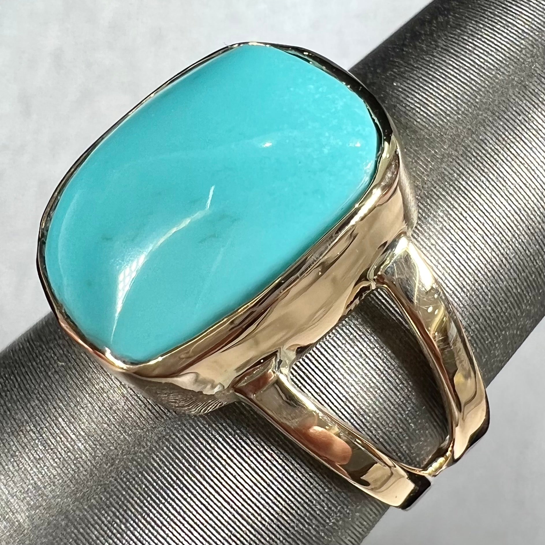 A handmade split shank ring set with Sleeping Beauty turquoise in yellow gold.