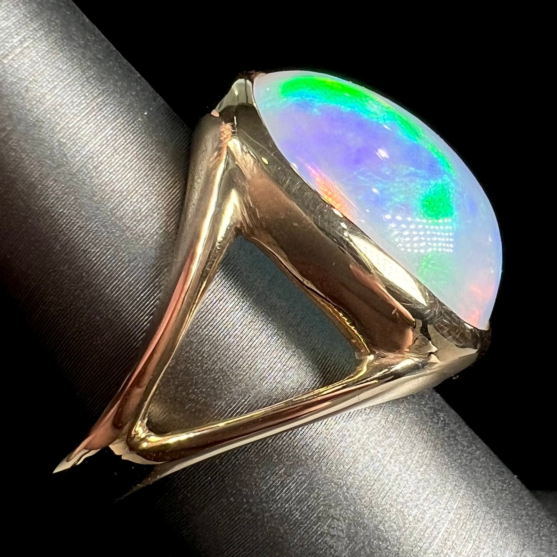 A gold split shank solitaire ring set with an oval cabochon cut 16.83 carat Ethiopian jelly fire opal.