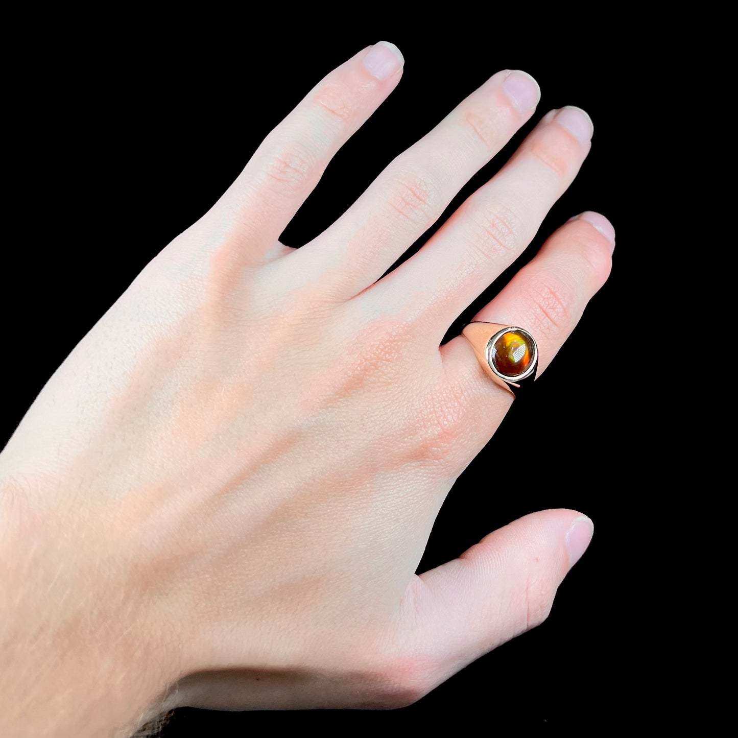 A unisex yellow gold flush set fire agate solitaire ring.