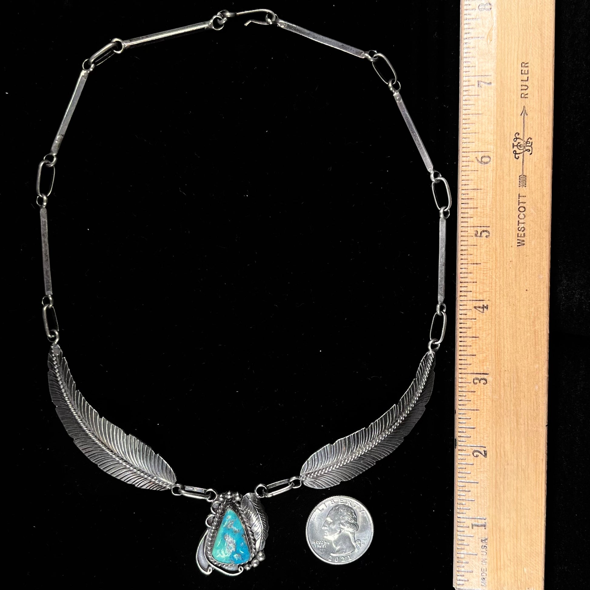 A sterling silver feather motif necklace set with a Sleeping Beauty turquoise stone, handmade by Navajo artist, Jameson Lee.