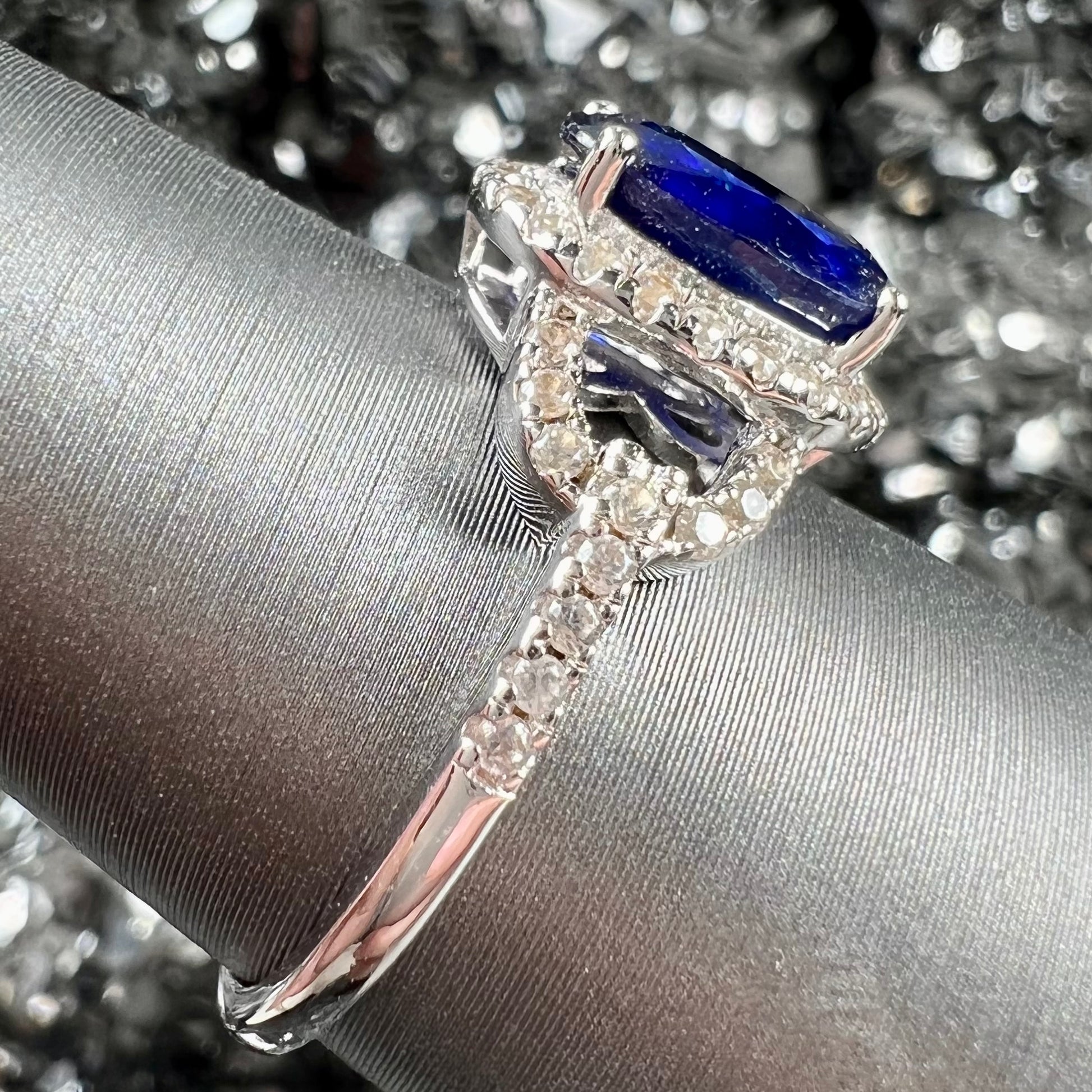 A sterling silver, white zircon halo ring set with an oval cut blue sapphire.