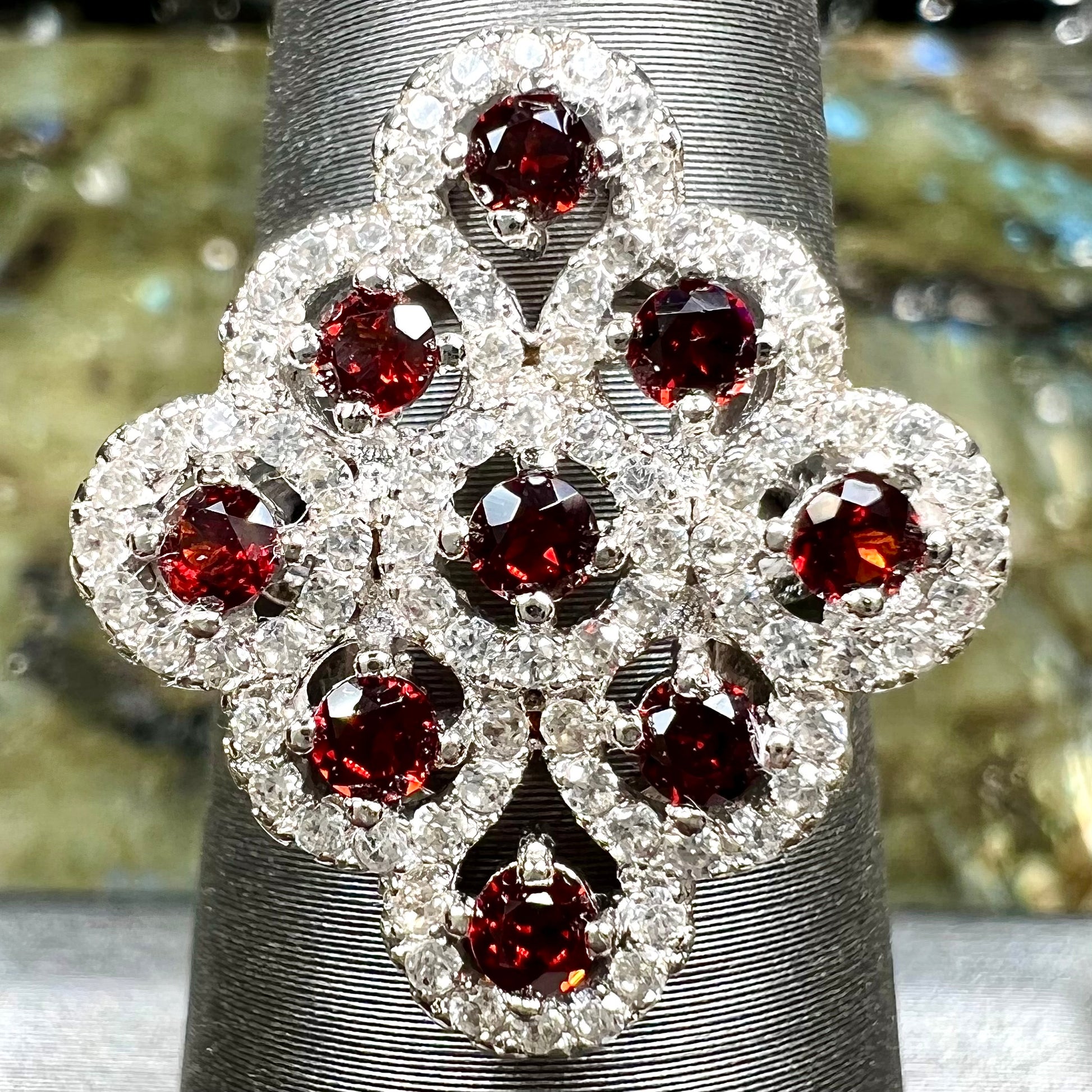 A sterling silver cluster ring set with round almandine garnet main stones and white zircon accents.