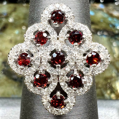 A sterling silver cluster ring set with round almandine garnet main stones and white zircon accents.