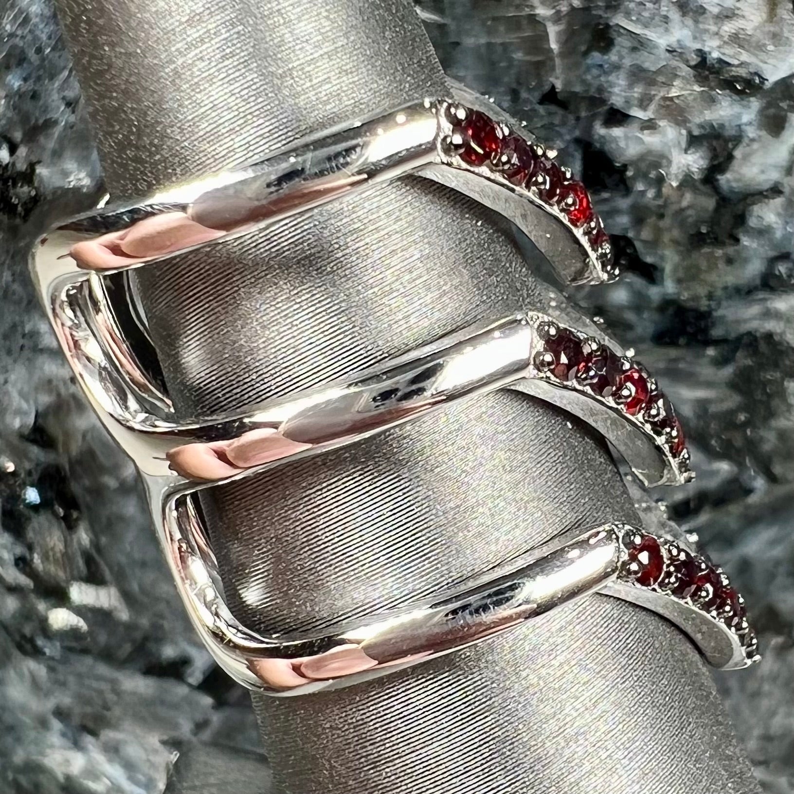 A sterling silver ring pave set with round almandine garnet stones.  The piece appears to be three rings in one.