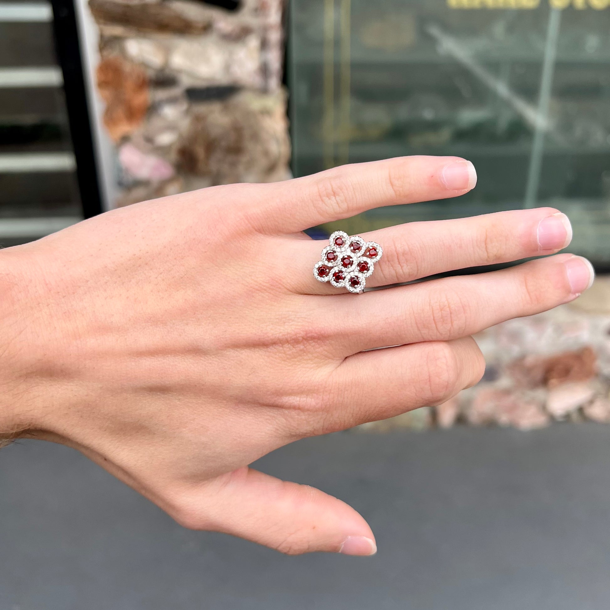 A sterling silver cluster ring set with round almandine garnet main stones and white zircon accents.