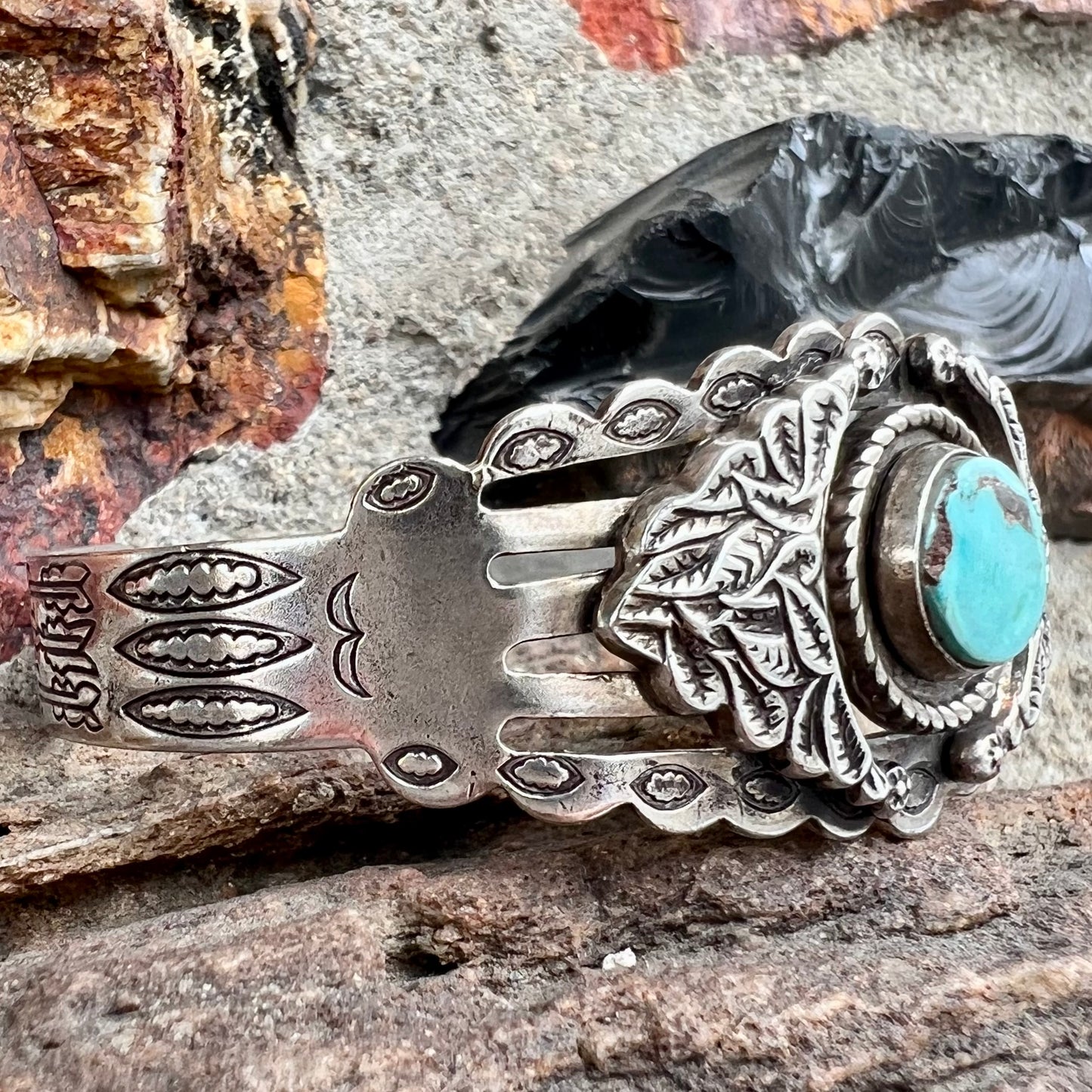 A base metal cuff bracelet set with a round cabochon cut imitation blue turquoise stone.