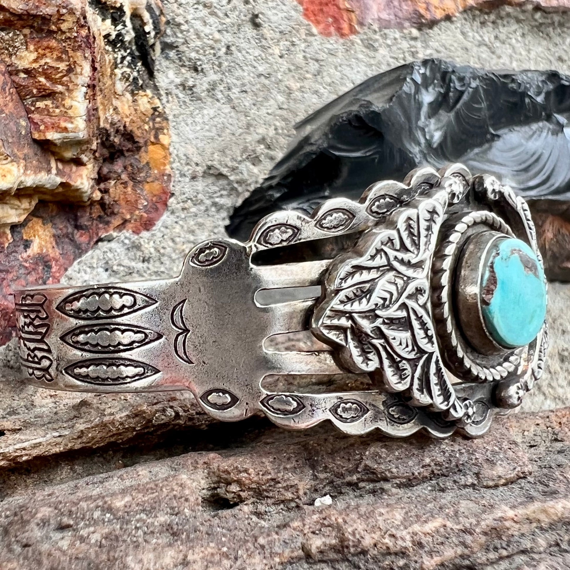 A base metal cuff bracelet set with a round cabochon cut imitation blue turquoise stone.