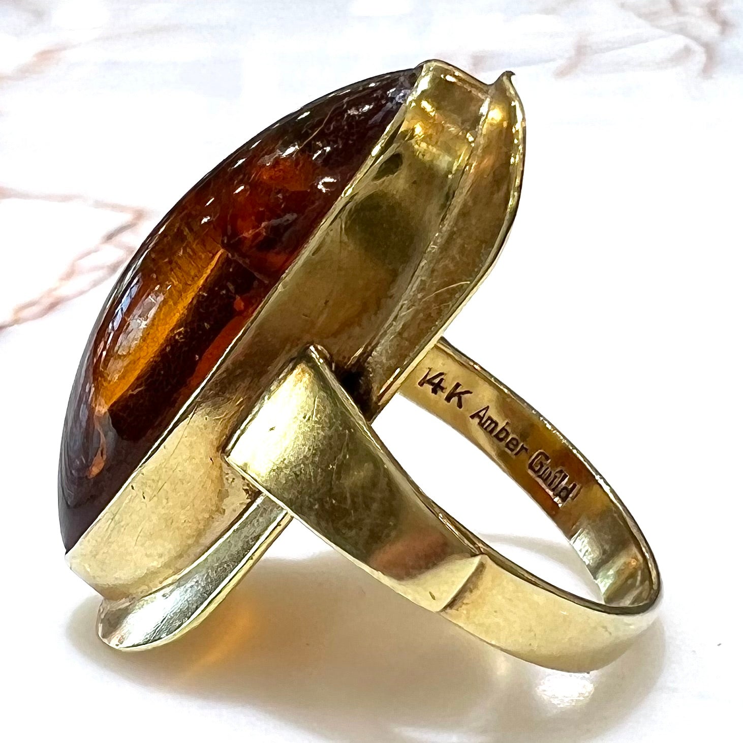 An oval cabochon cut Baltic amber stone set in a yellow gold ring and stamped "AMBER GUILD."