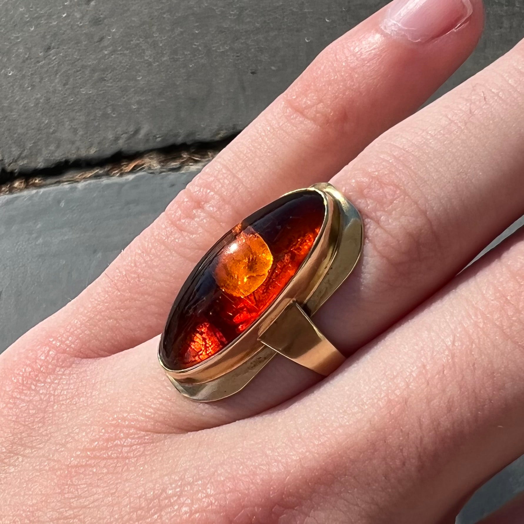 An oval cabochon cut Baltic amber stone set in a yellow gold ring and stamped "AMBER GUILD."