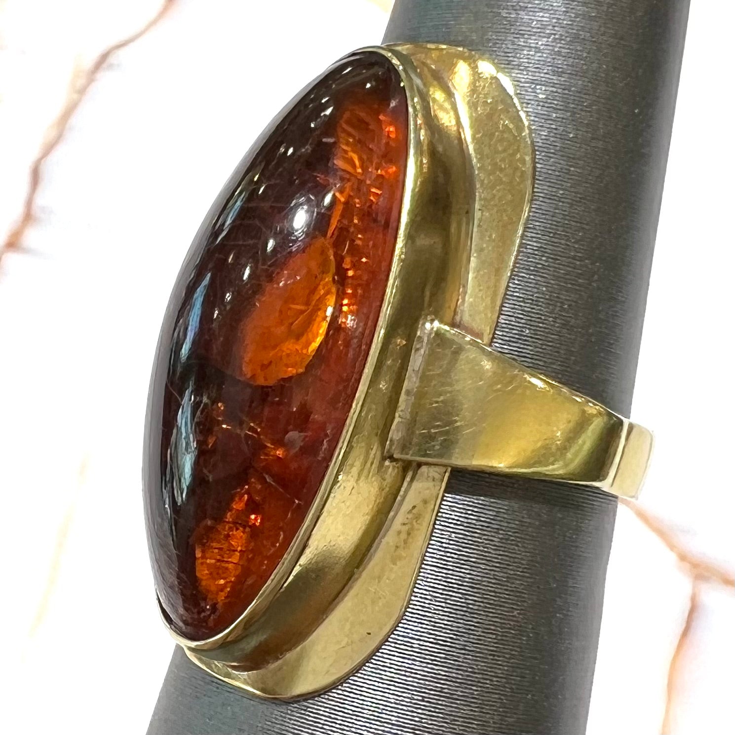 An oval cabochon cut Baltic amber stone set in a yellow gold ring and stamped "AMBER GUILD."