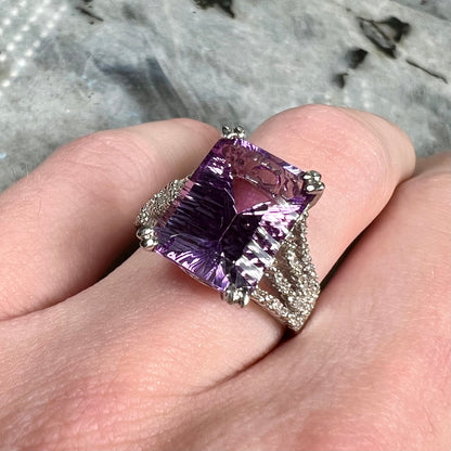 A white gold ladies ring set with an emerald laser cut amethyst and diamond chip accents.