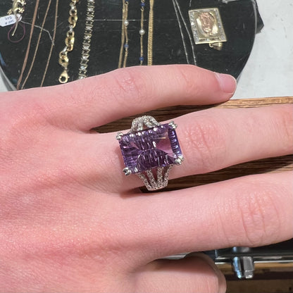 A white gold ladies ring set with an emerald laser cut amethyst and diamond chip accents.