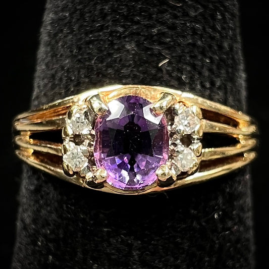 A ladies split shank gold ring set with an oval cut amethyst and round brilliant diamond accents.