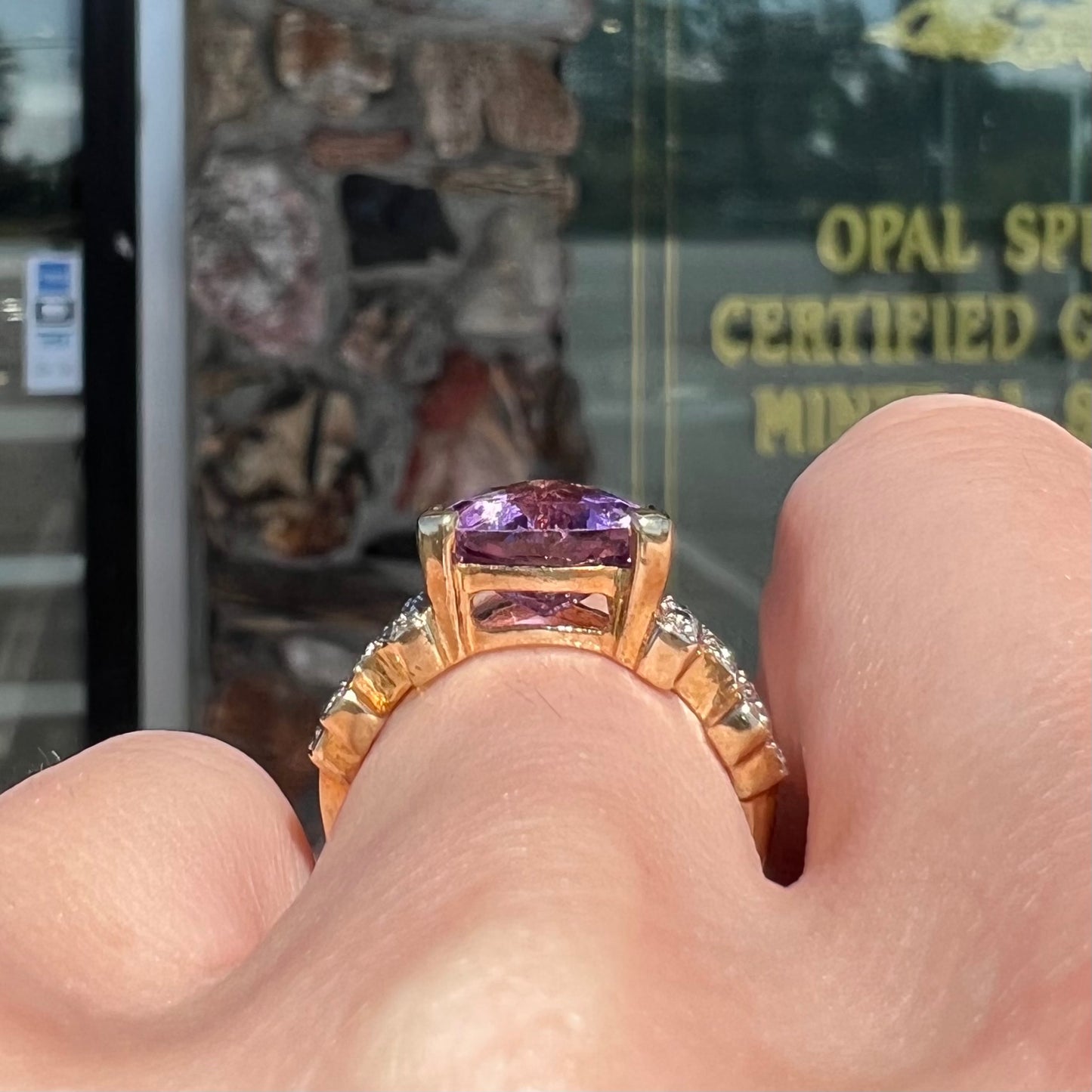 A yellow gold ring set with a trillion cut amethyst and round diamond accent stones.