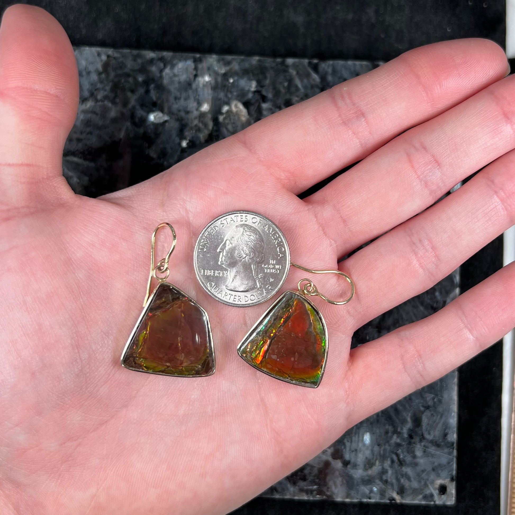 Yellow gold French wire dangle earrings bezel set with two polished freeform cut red ammolite fossils.