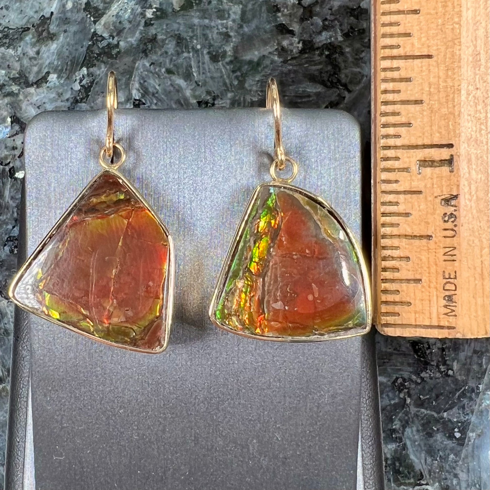 Yellow gold French wire dangle earrings bezel set with two polished freeform cut red ammolite fossils.
