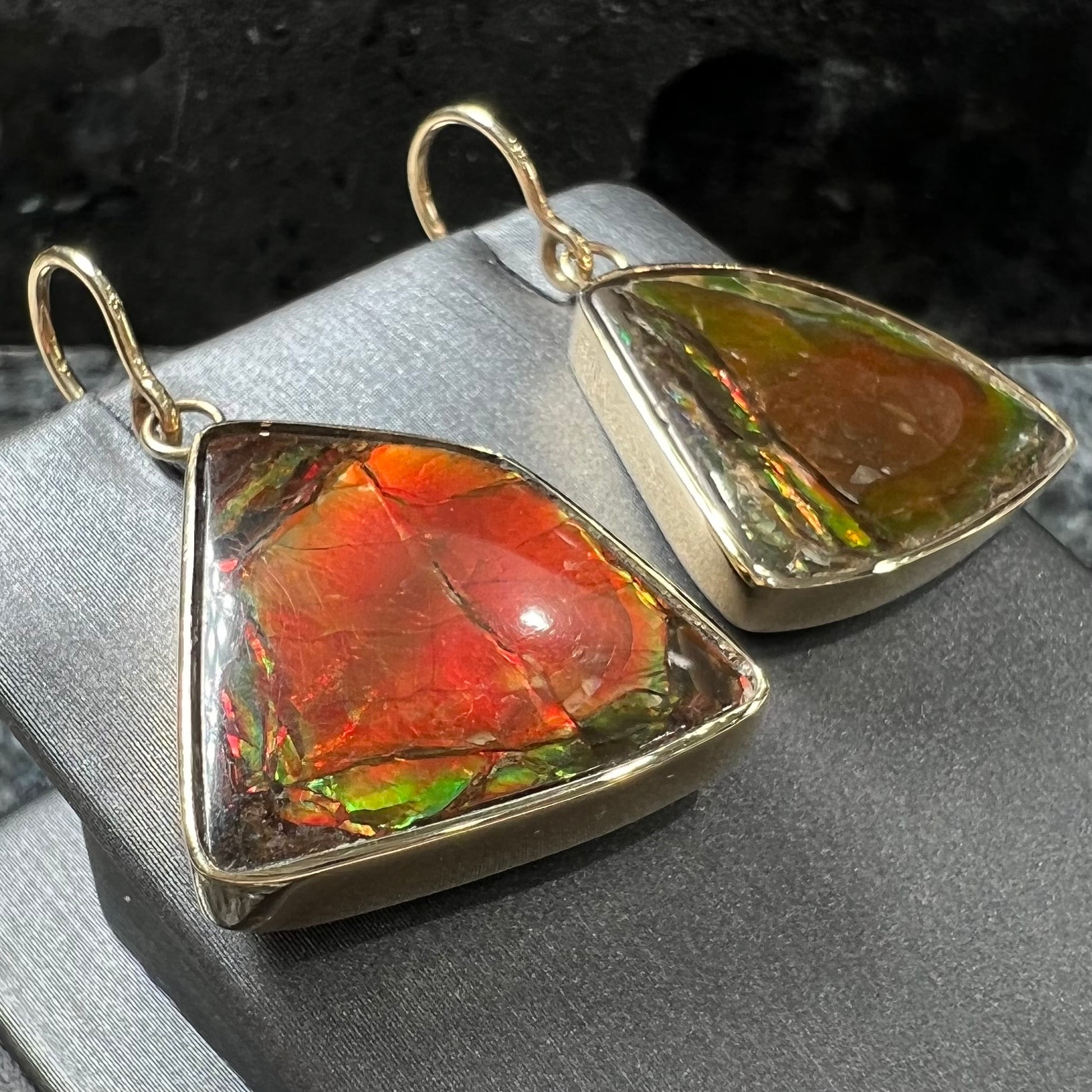 Yellow gold French wire dangle earrings bezel set with two polished freeform cut red ammolite fossils.