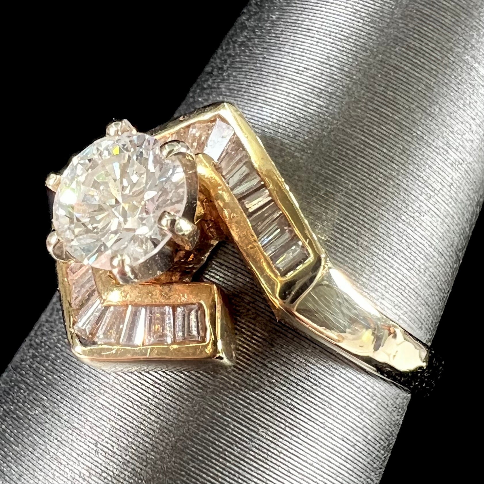 A gold diamond ring set with a round cut center stone with channel set baguette cut accent stones.