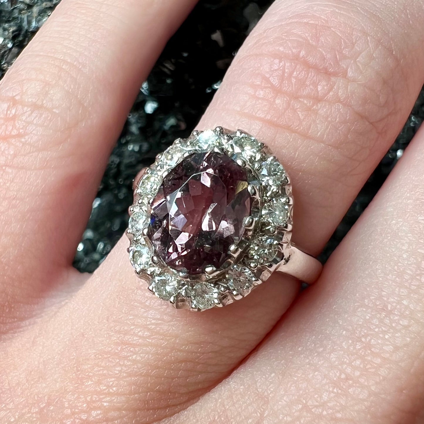 A white gold diamond halo ring set with a purplish faceted oval cut color change garnet.