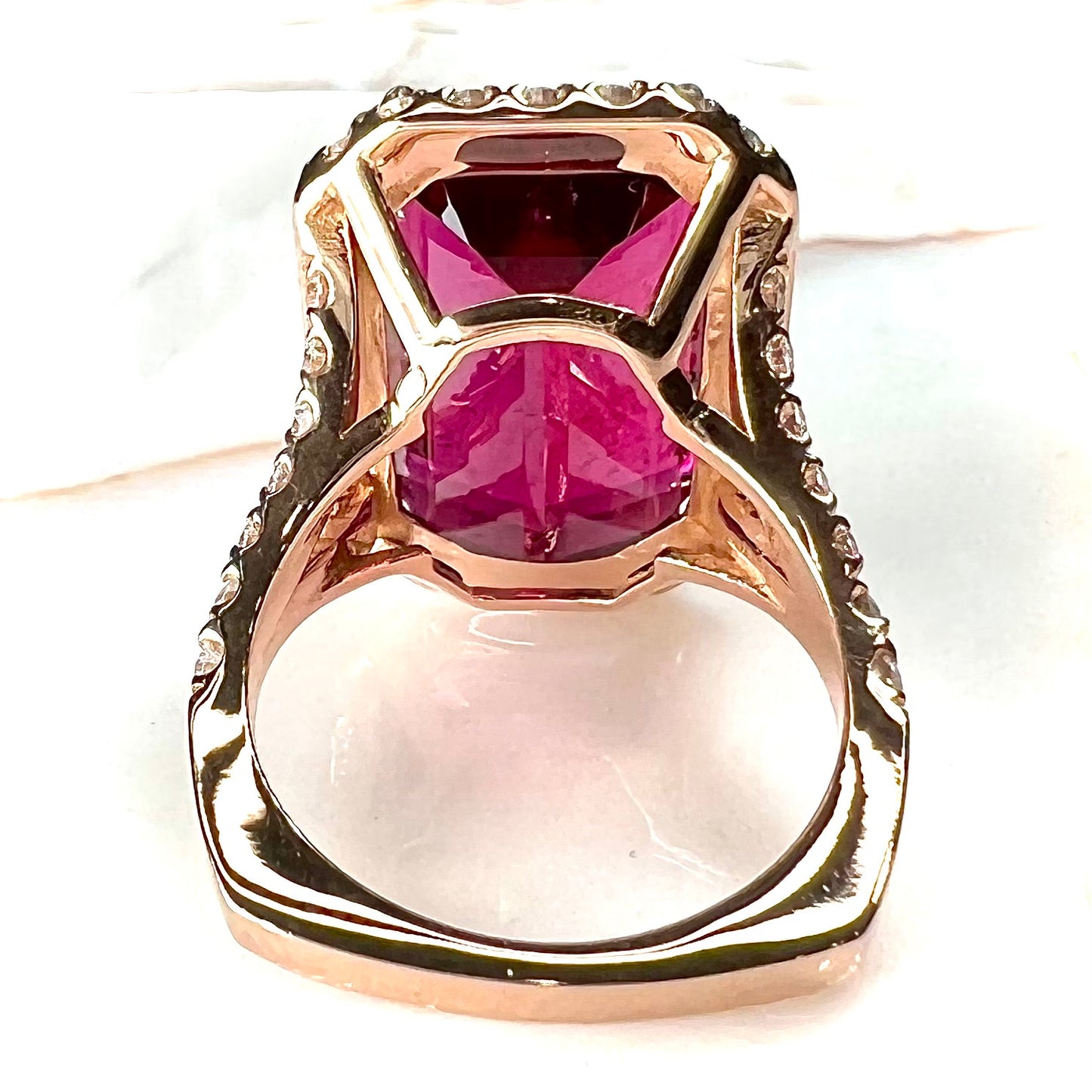 Red emerald cut rubellite tourmaline gemstone set with near flawless round cut diamonds in rose gold.