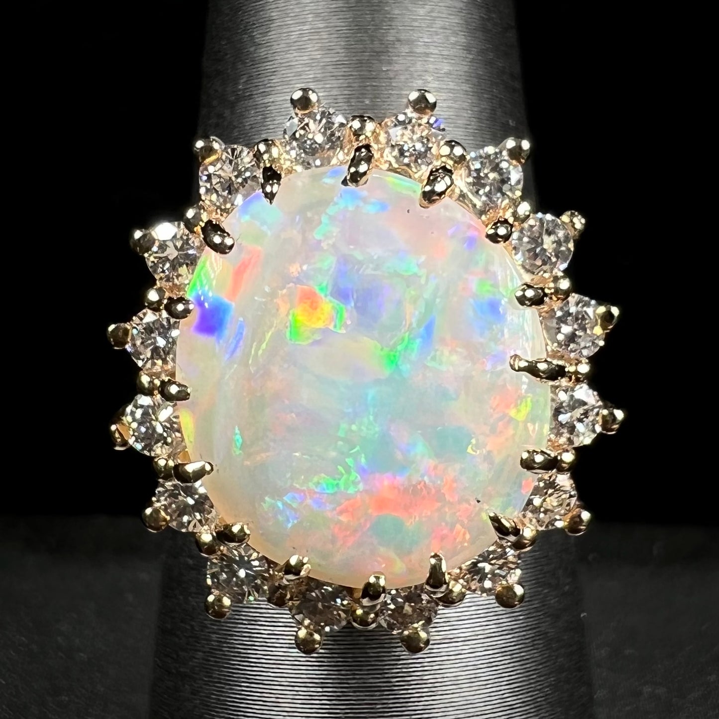 A ladies' diamond halo ring set with a Coober Pedy opalized seashell in yellow gold.