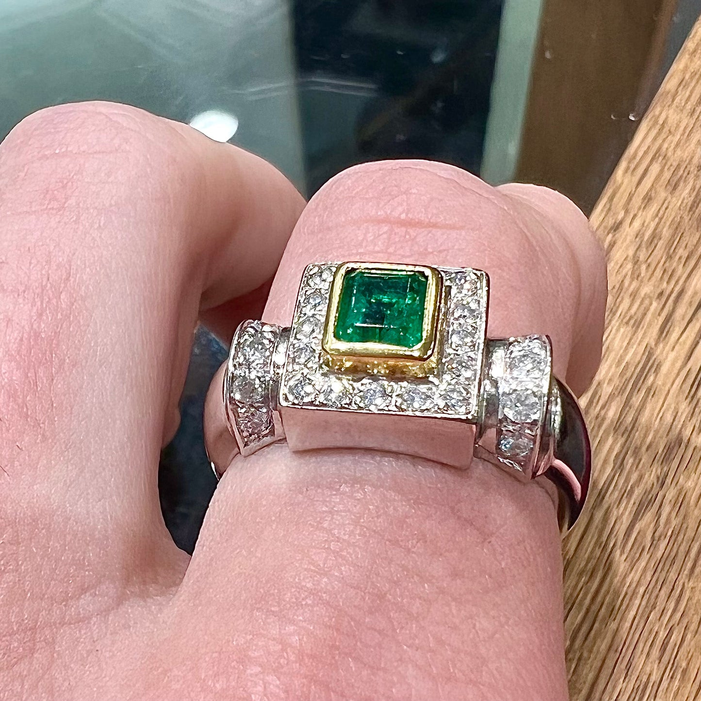 A two tone gold emerald and diamond halo ring.