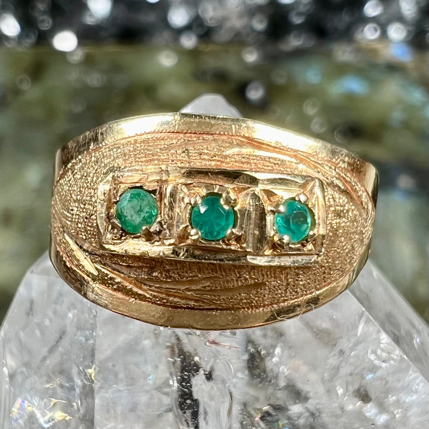 A 1920's style yellow gold three stone round cut emerald ring.