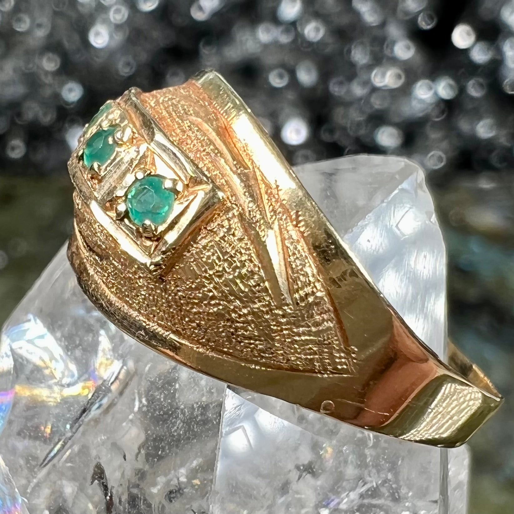 A 1920's style yellow gold three stone round cut emerald ring.