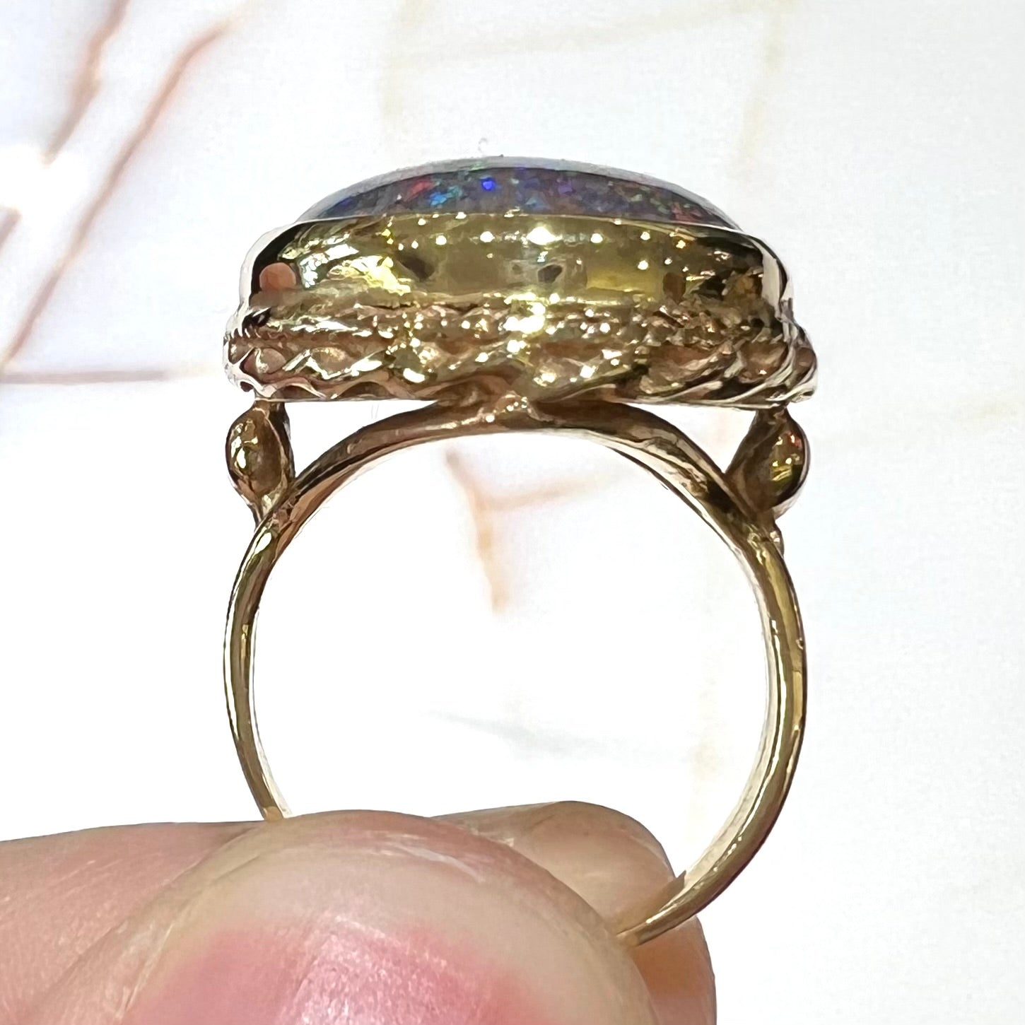 A bright black Andamooka opal that displays a pinfire pattern set in a vintage-style yellow gold bezel ring.