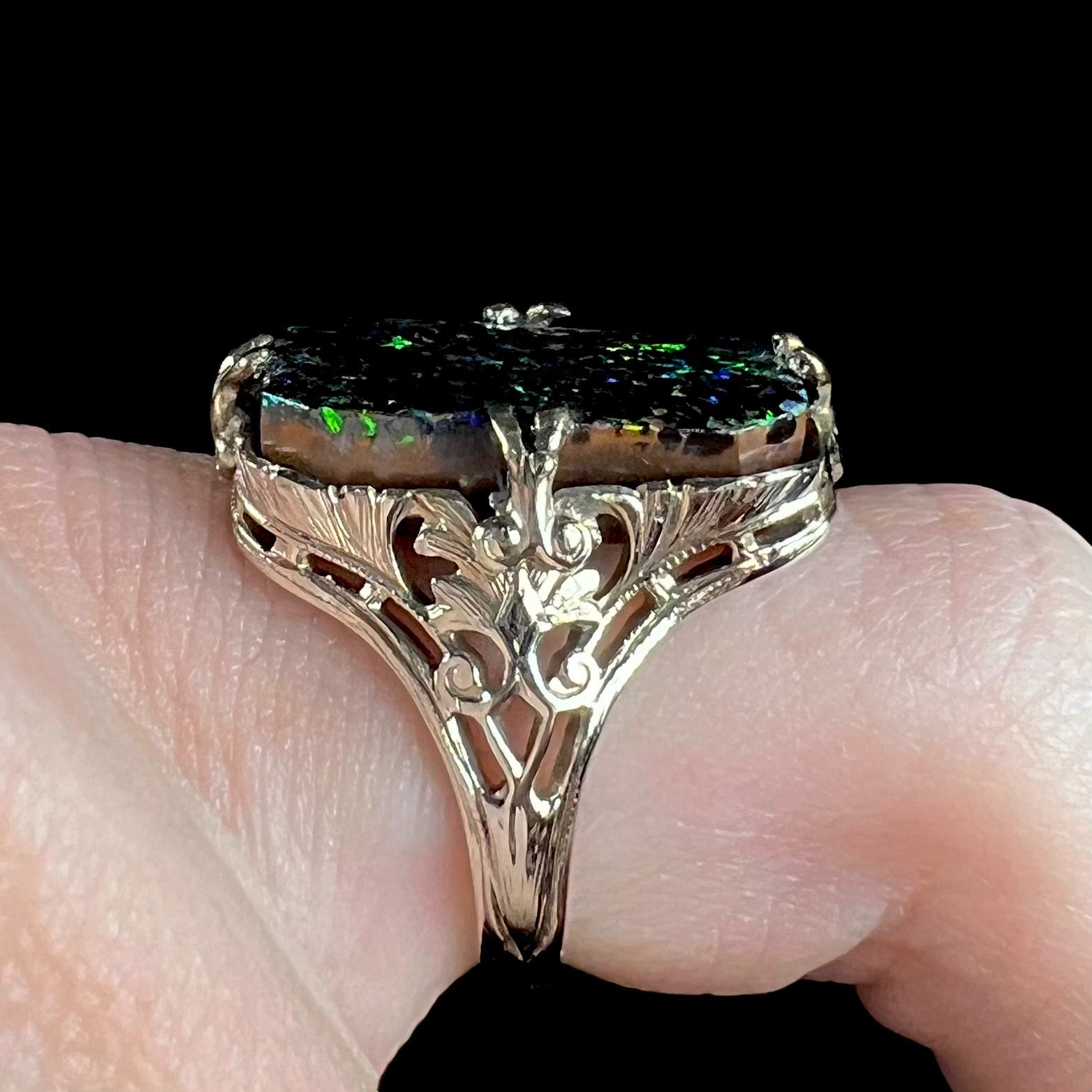 A vintage, white gold filigree unisex ring set with a natural black Koroit boulder opal.