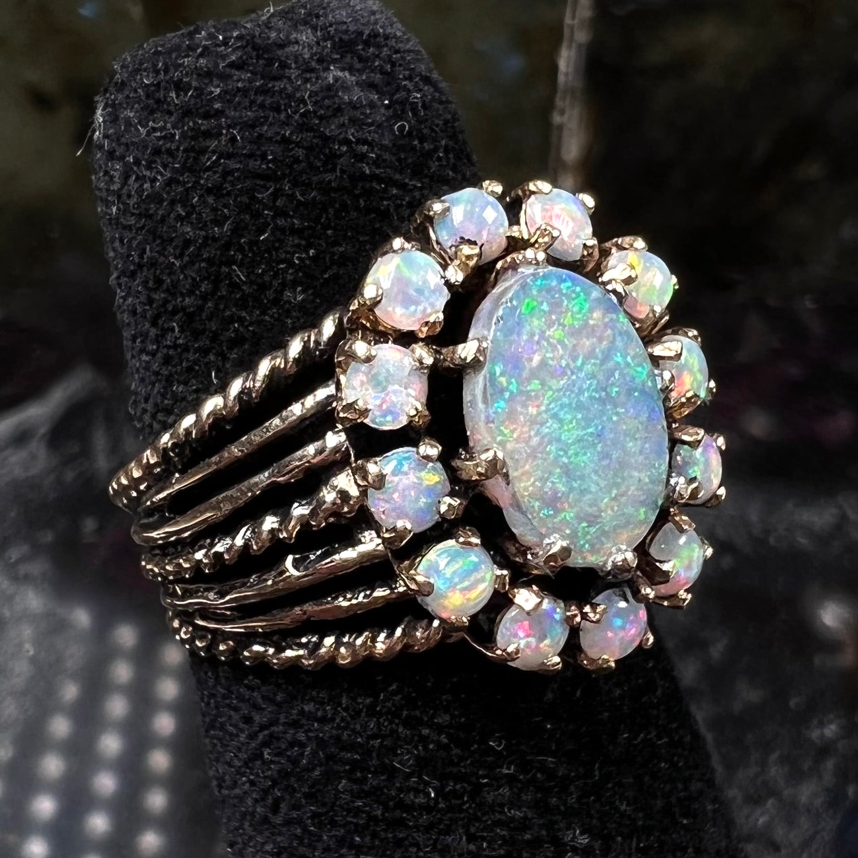 Vintage yellow gold oval opal cabochon ring set with 12 round opals in a halo around the center stone.