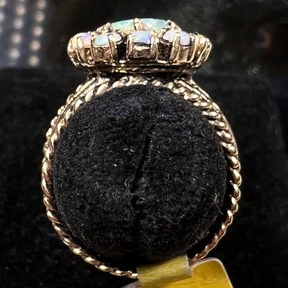 Vintage yellow gold oval opal cabochon ring set with 12 round opals in a halo around the center stone.