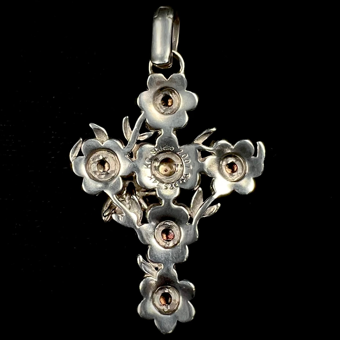 A cross pendant with floral decoration.  The cross is made of six  flowers with sterling silver petals and yellow gold nectar.  A silver bee is on one of the pendants.  The bail opens and closes.