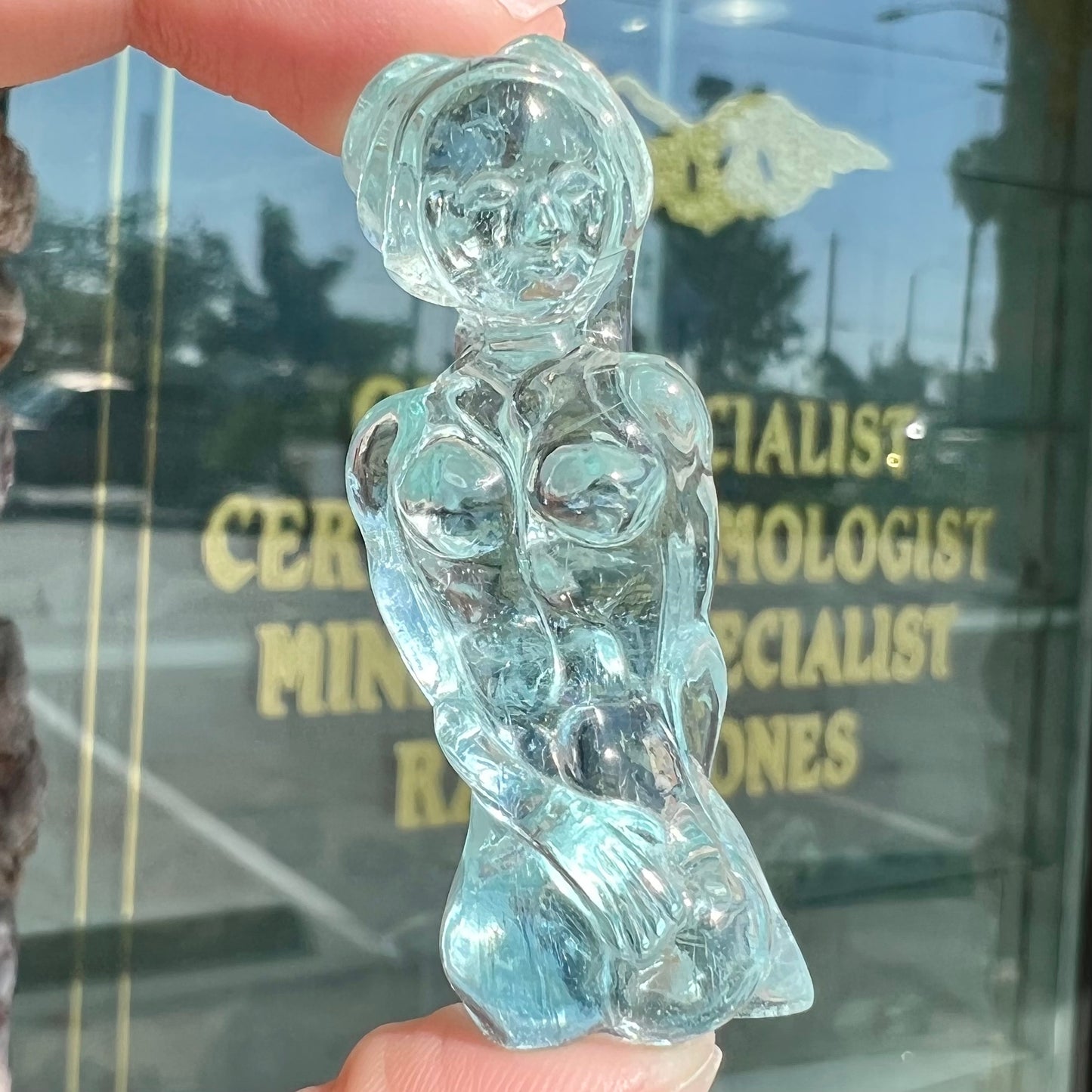 A stone woman figure carved from a blue aquamarine crystal.  The piece resembles Venus Gummi de Milo.