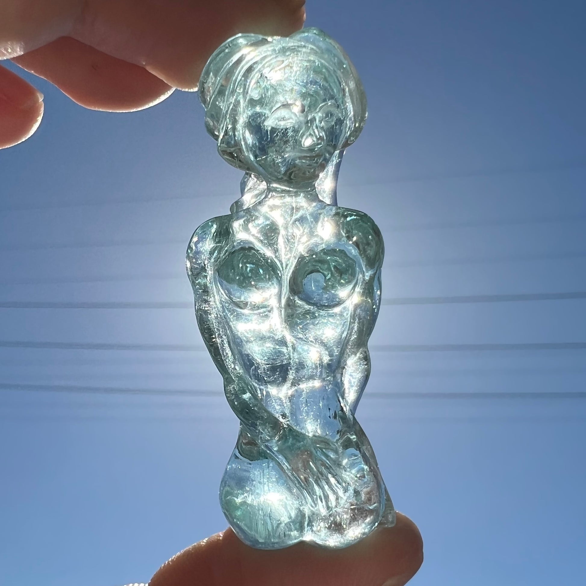 A stone woman figure carved from a blue aquamarine crystal.  The piece resembles Venus Gummi de Milo.