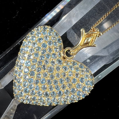 A gold heart pendant pave set with round aquamarine stones.