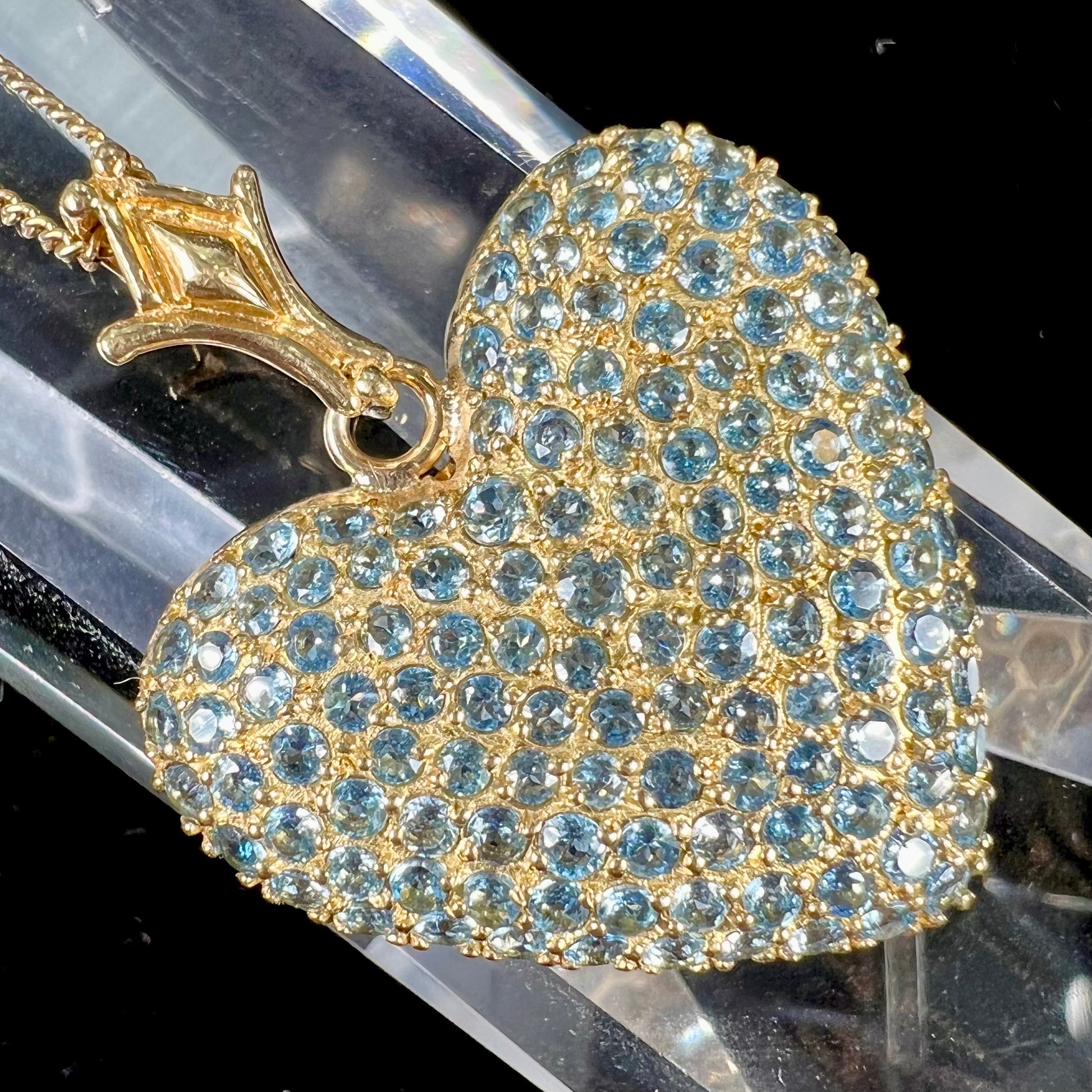 A gold heart pendant pave set with round aquamarine stones.