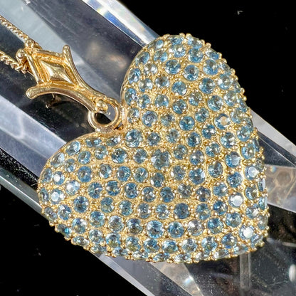 A gold heart pendant pave set with round aquamarine stones.