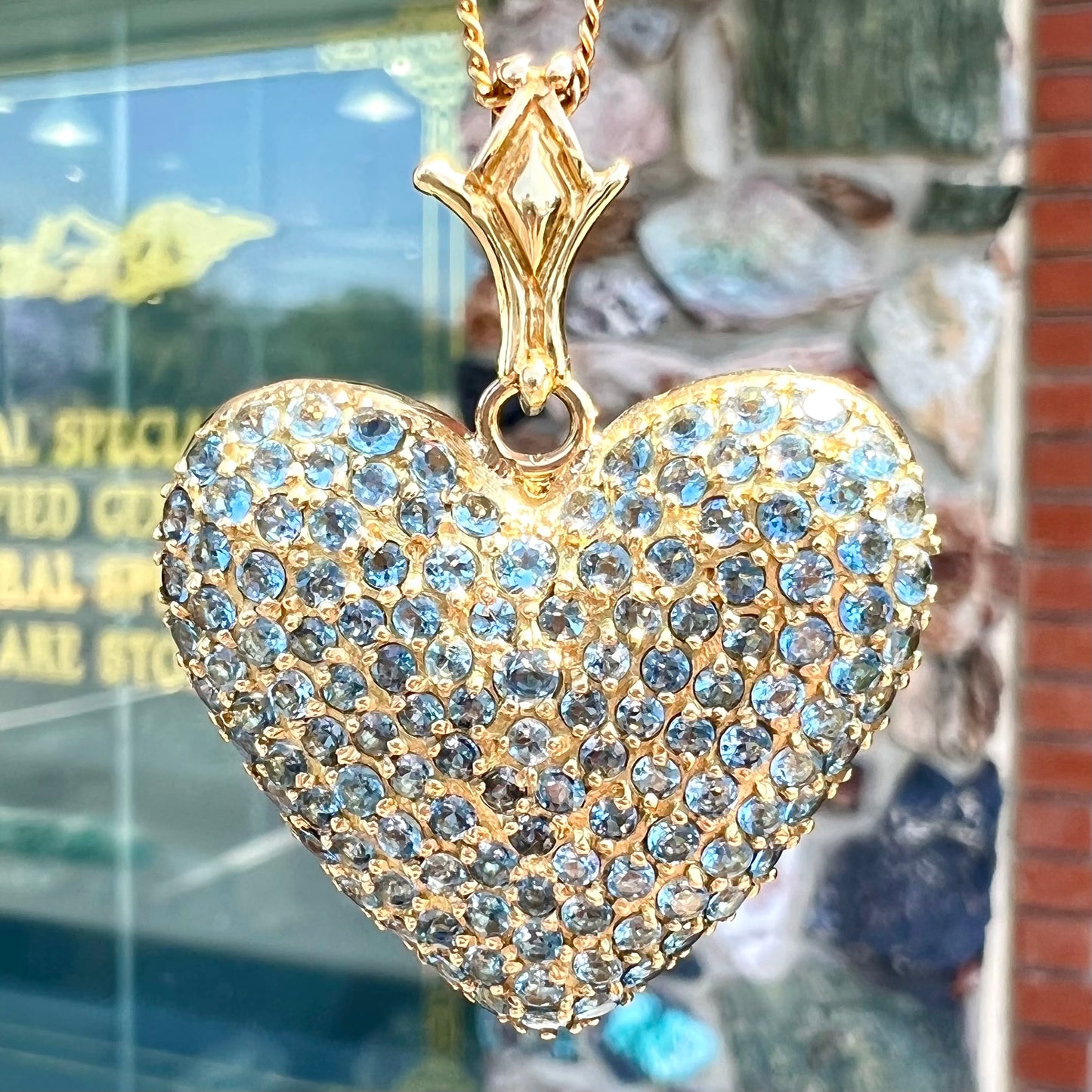 A gold heart pendant pave set with round aquamarine stones.