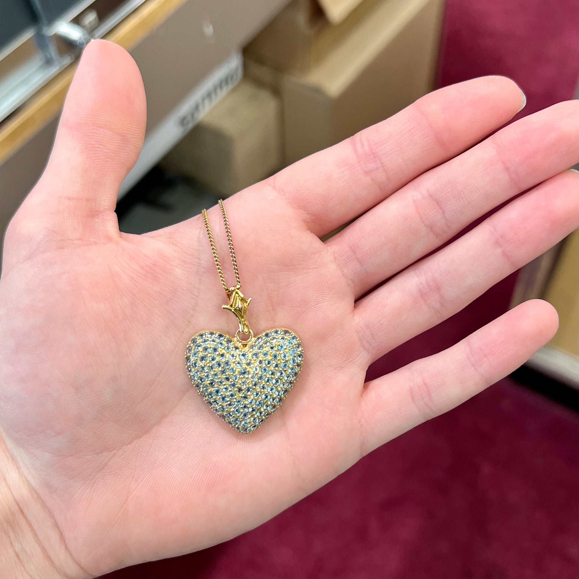 A gold heart pendant pave set with round aquamarine stones.