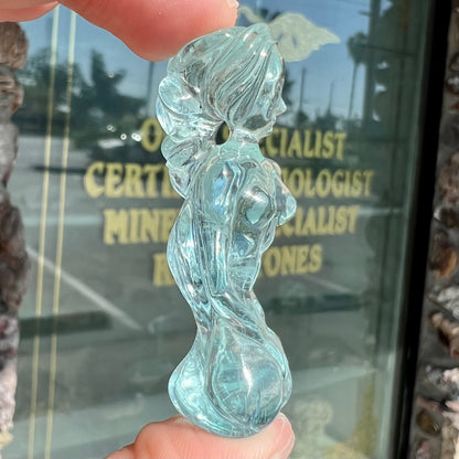 A stone woman figure carved from a blue aquamarine crystal.  The piece resembles Venus Gummi de Milo.