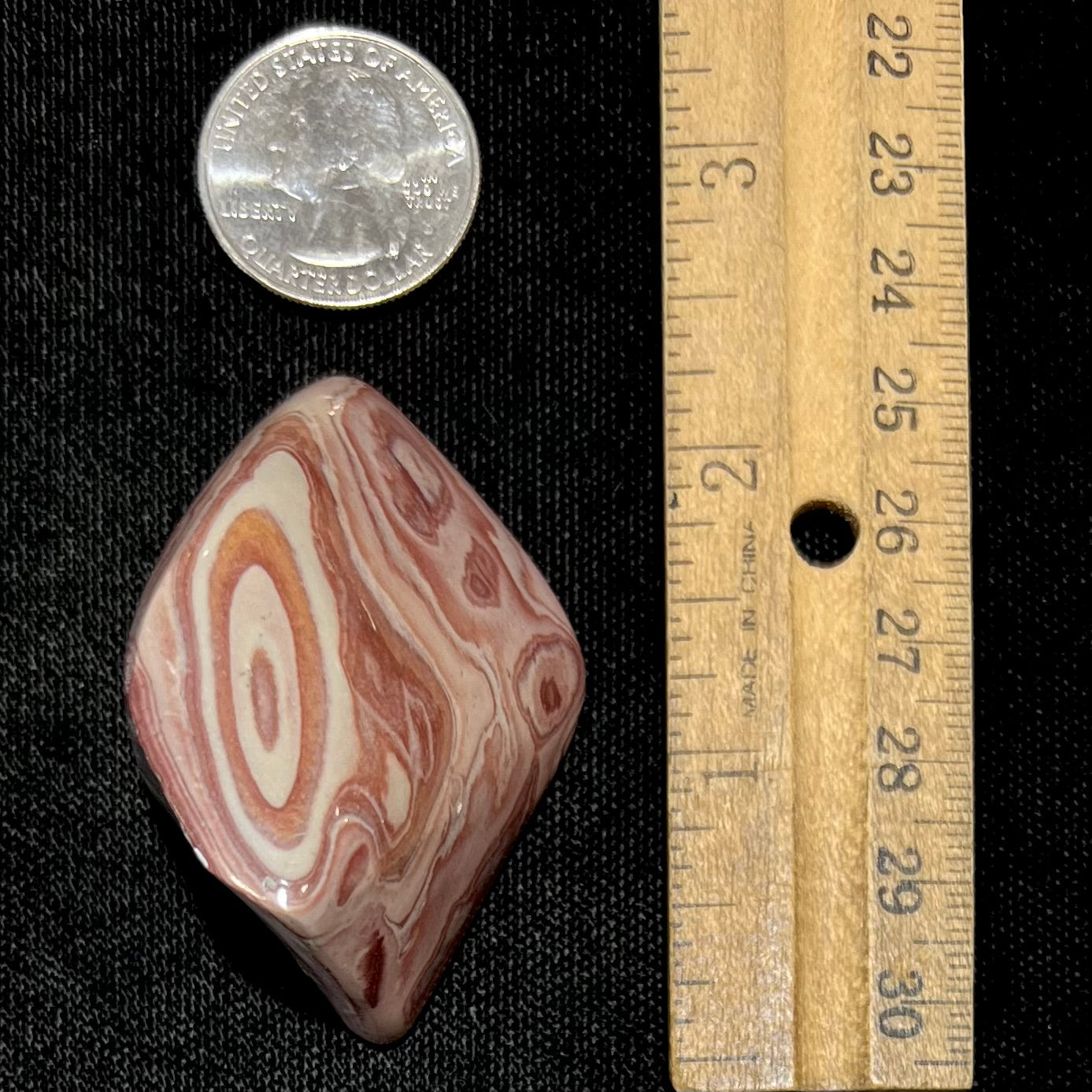 A polished piece of pinkish red picture jasper.  The stone displays a bull's eye pattern.