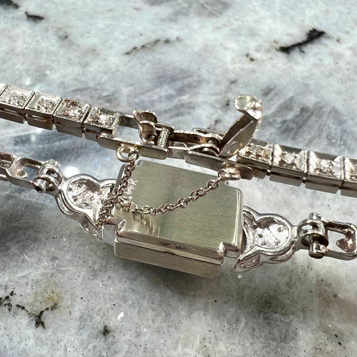 A vintage, art deco style white gold and diamond bracelet set with a rectangular shape black boulder opal stone.